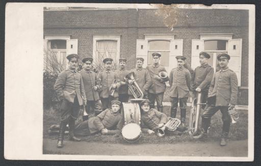 [Militärmusikanten vor Backsteinhaus]