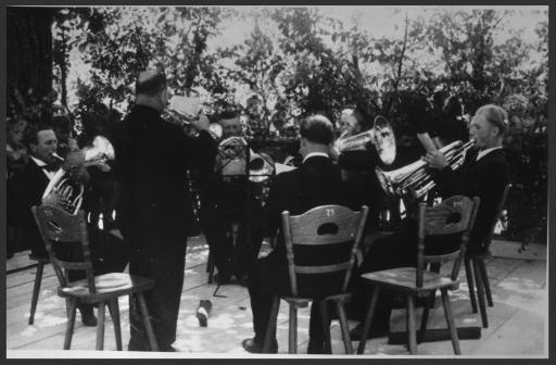 [Kapelle Hartner im Kreis sitzend mit Musikinstrumenten]