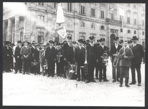 [Blaskapelle mit Fahne und Instrumenten vor Würzburger Residenz]